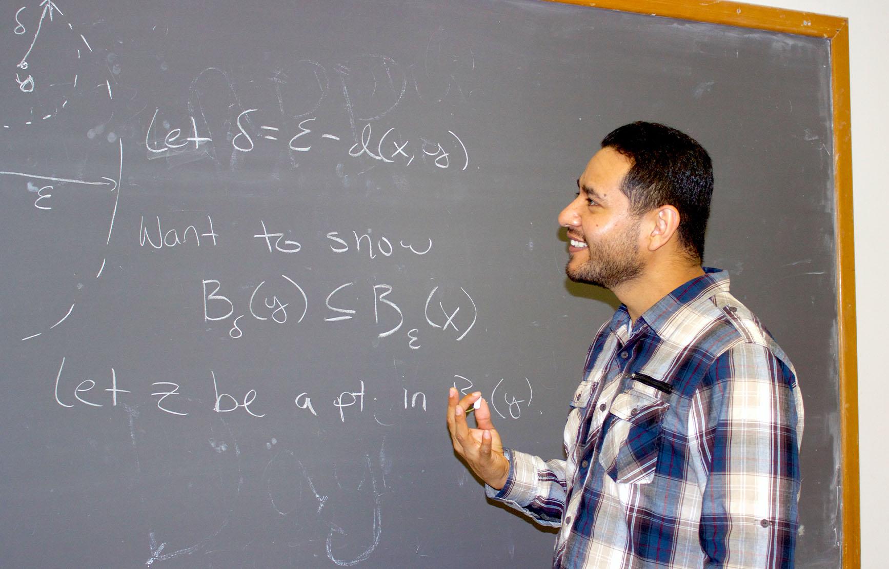 Michael Lopez writing equations on blackboard.