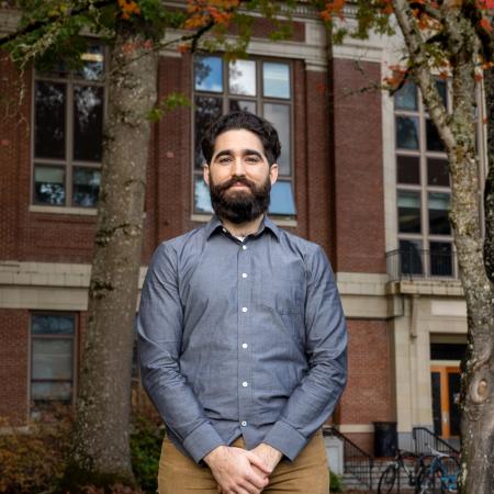 Fernando Angulo Barba stands in a blue shirt and khaki pants in front of Kidder Hall.