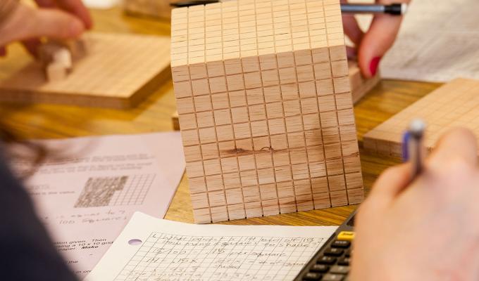 wooden cube on a table with math homework