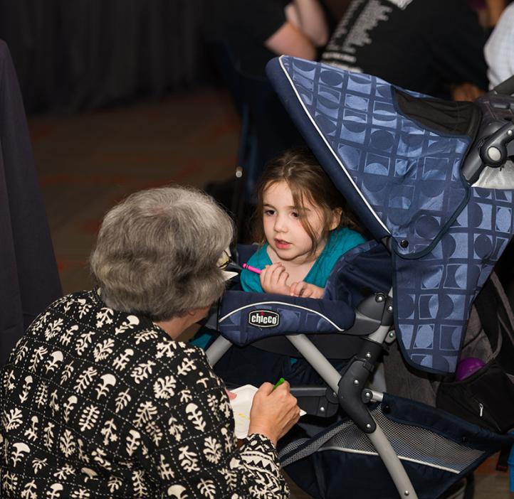 Young toddler in stroller chatting with elderly woman